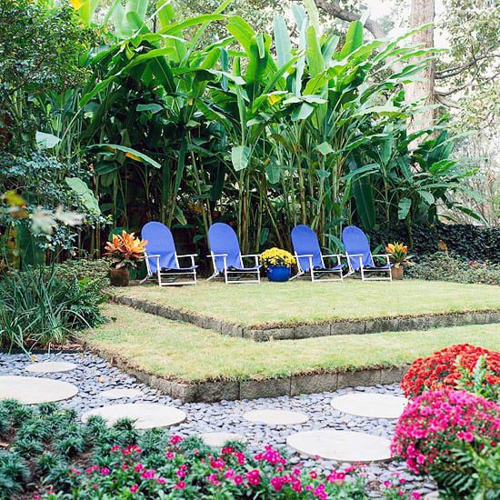 Blue lounge chairs on a lawn terrace framed by lush green planting