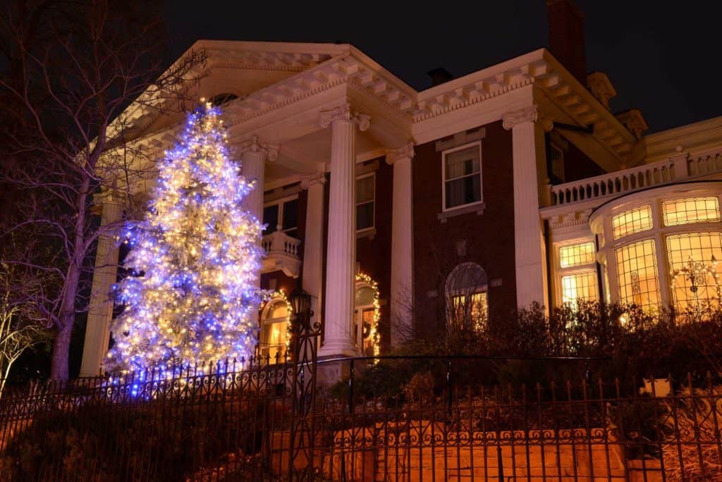 large illuminated holiday tree in front of estate