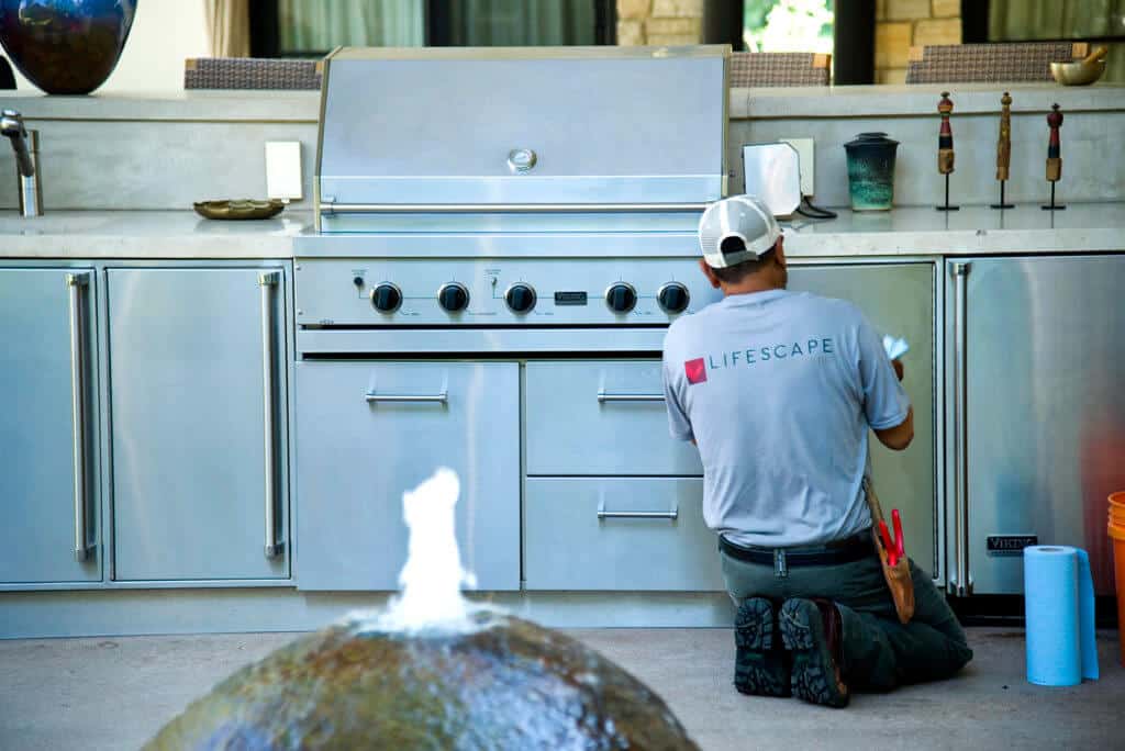 worker cleaning outdoor kitchen grill