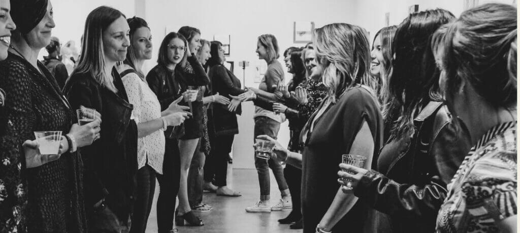 black and white photo of a group of women networking and talking at an event