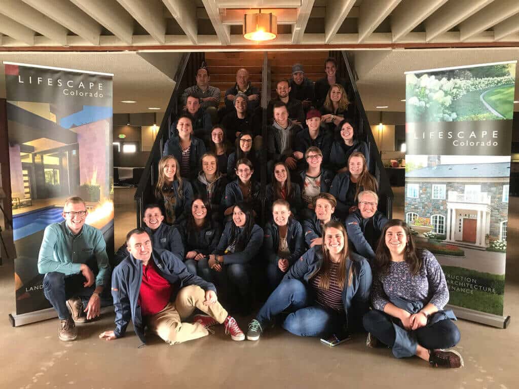 large group of Lifescape Colorado team members posing on a set of stairs between two promotional banners