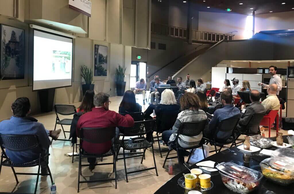lifescape Colorado team meeting with a presentation screen in a large, modern office space with tiered seating in the background