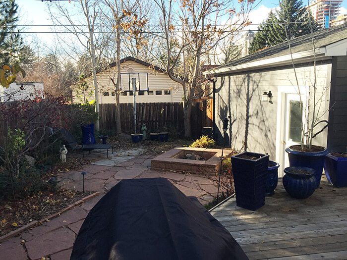 backyard patio with flagstone, a fire pit, several large blue planters, and a wooden deck in the foreground