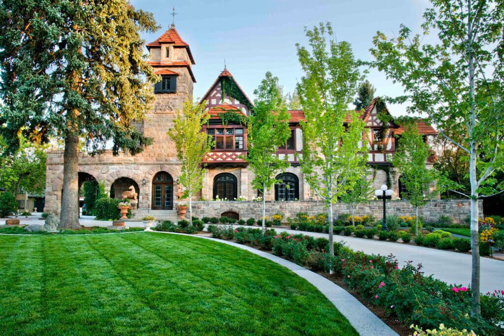 grand, Tudor-style stone mansion with a prominent turret