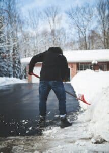 man shovels snow off driveway