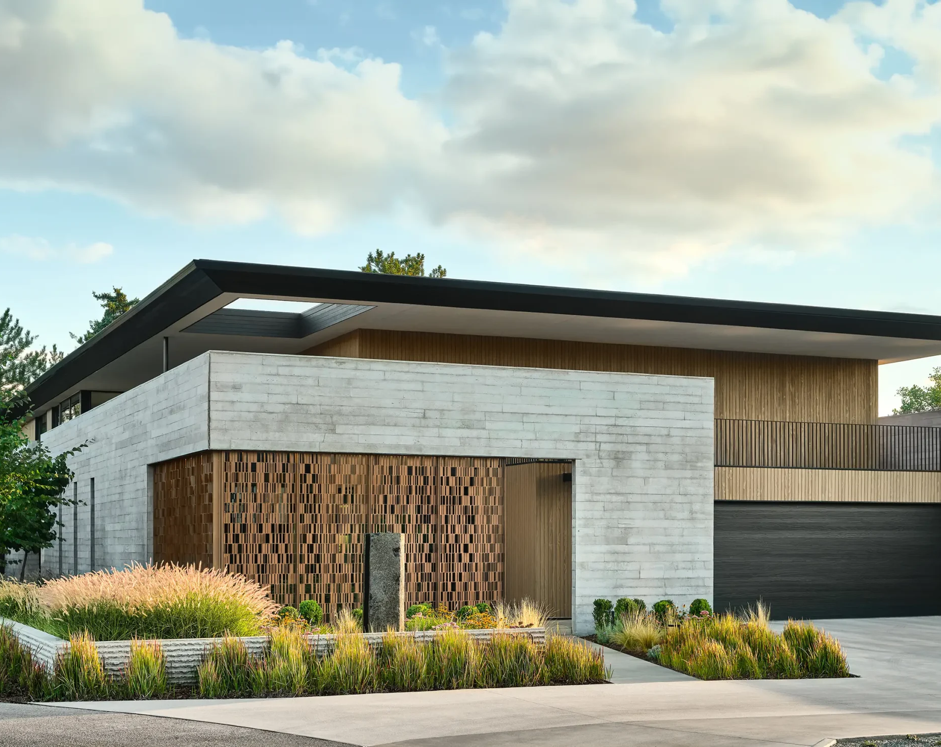 Modern Colorado home with concrete and wood facade surrounded by drought-tolerant ornamental grass landscaping