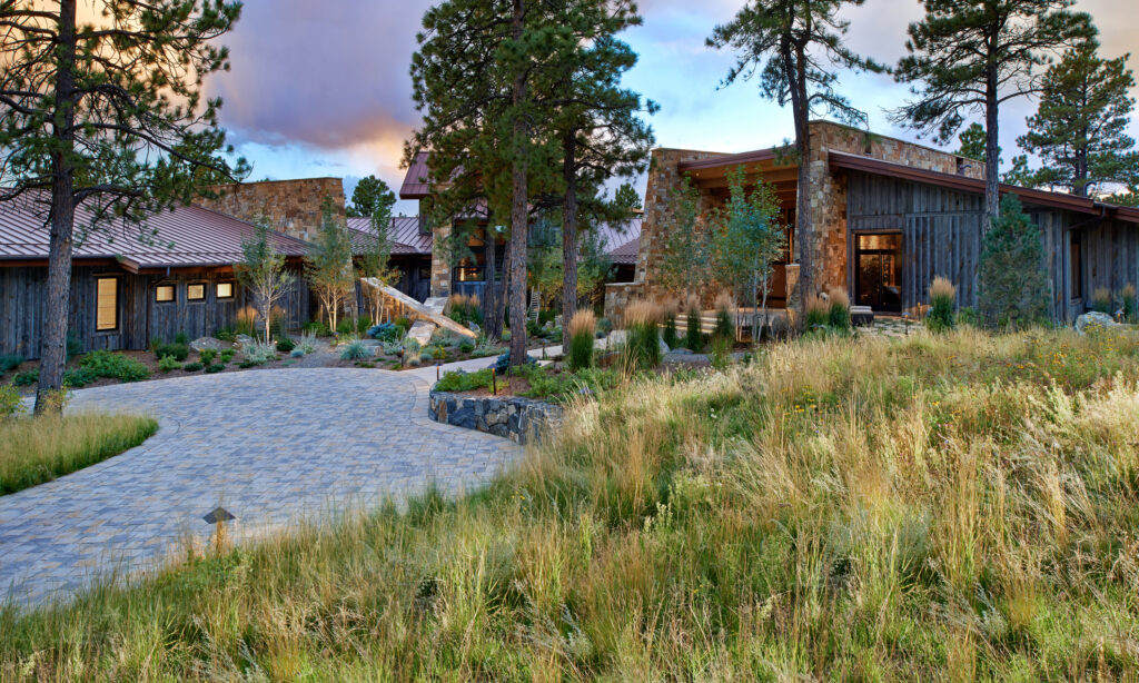 Mountain home with stone and wood exterior surrounded by native grass meadow and pine trees